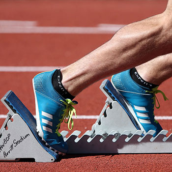 immagine dei piedi di un atleta ai blocchi di partenza