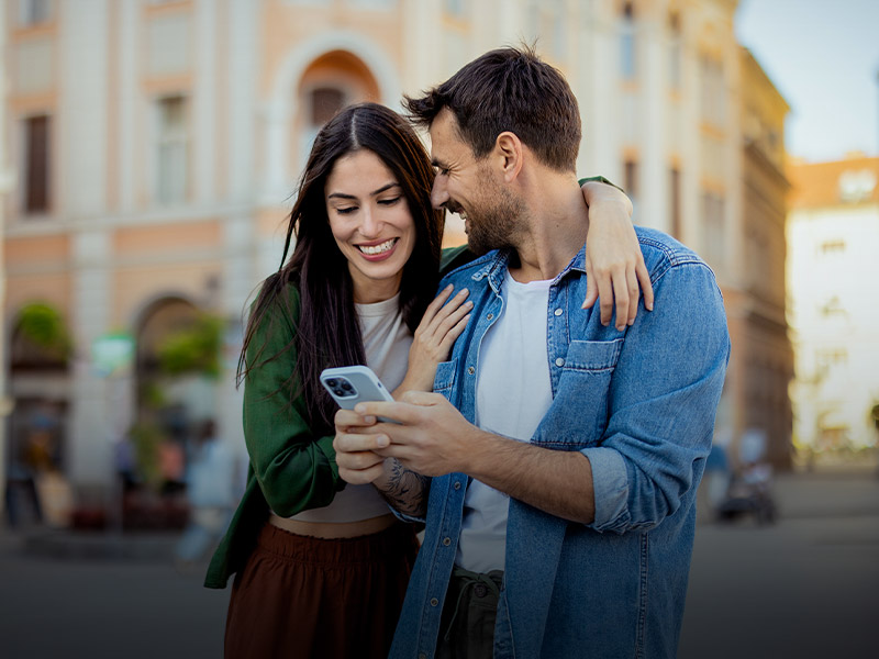 Una ragazza e un ragazzo abbracciati guardano un cellulare