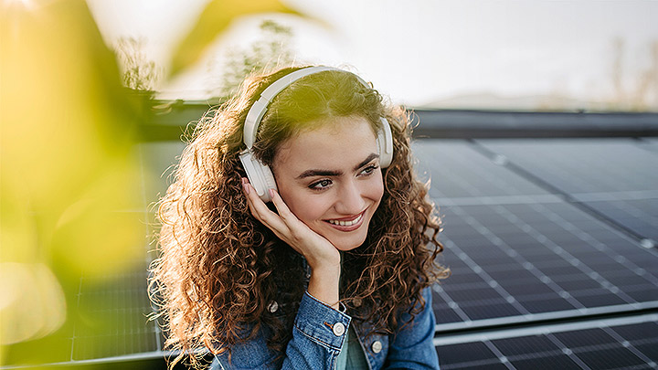 Mutuo BNL Green: primo piano di una giovane donna sorridente, pannelli fotovoltaici sullo sfondo