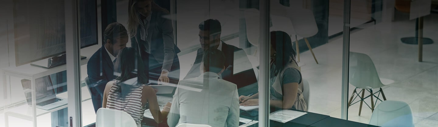 gruppo di colleghi e colleghe al lavoro intorno a un tavolo in una sala riunioni